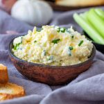 Garlic cheddar cheese dip served in a bowl with toasted bread and celery.
