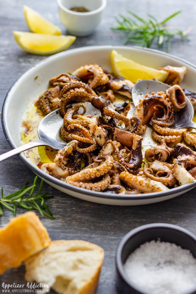 Marinated baby octopus with lemon wedges and baguette.