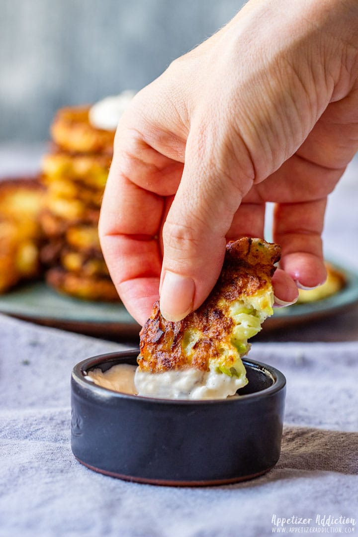 Dipping zucchini fritters to the sauce.
