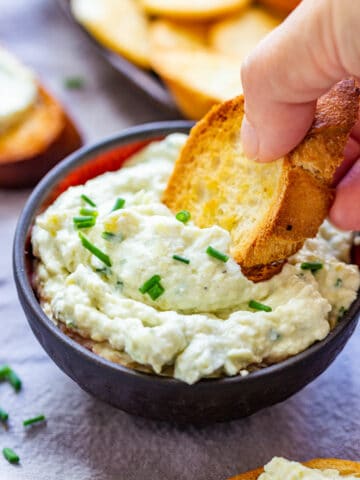 Scooping artichoke parmesan dip with crostini