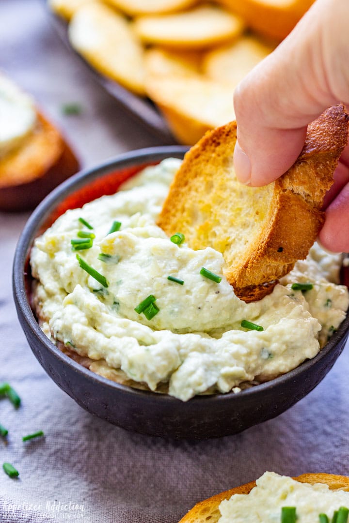 Scooping artichoke parmesan dip with crostini