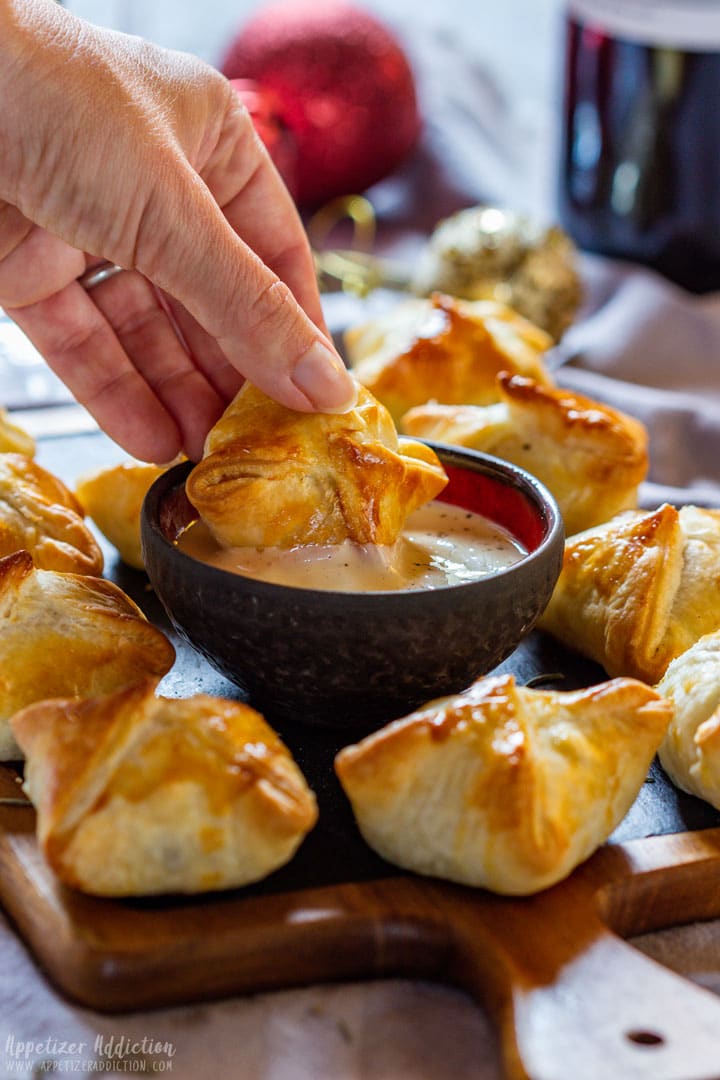 Dipping beef wellington bites to the sauce