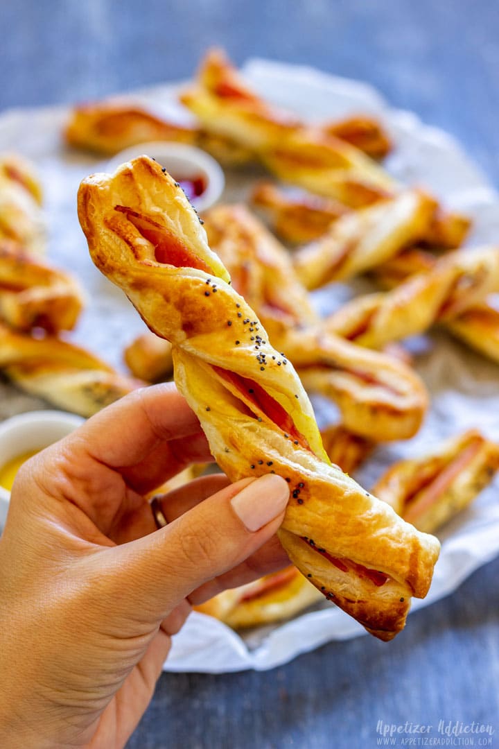 Holding bacon puff pastry twists, ready to take a bite