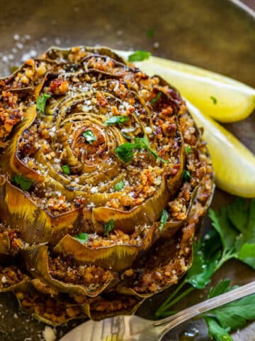 Stuffed artichoke on the plate with slices of lemon