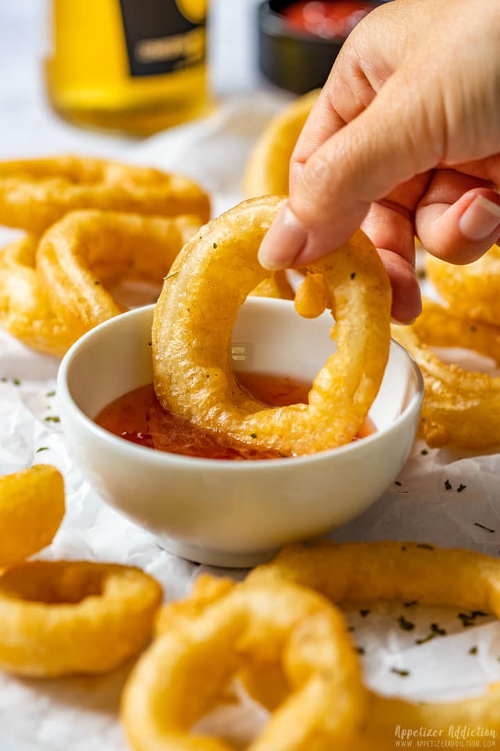 Dipping onion ring into the sauce