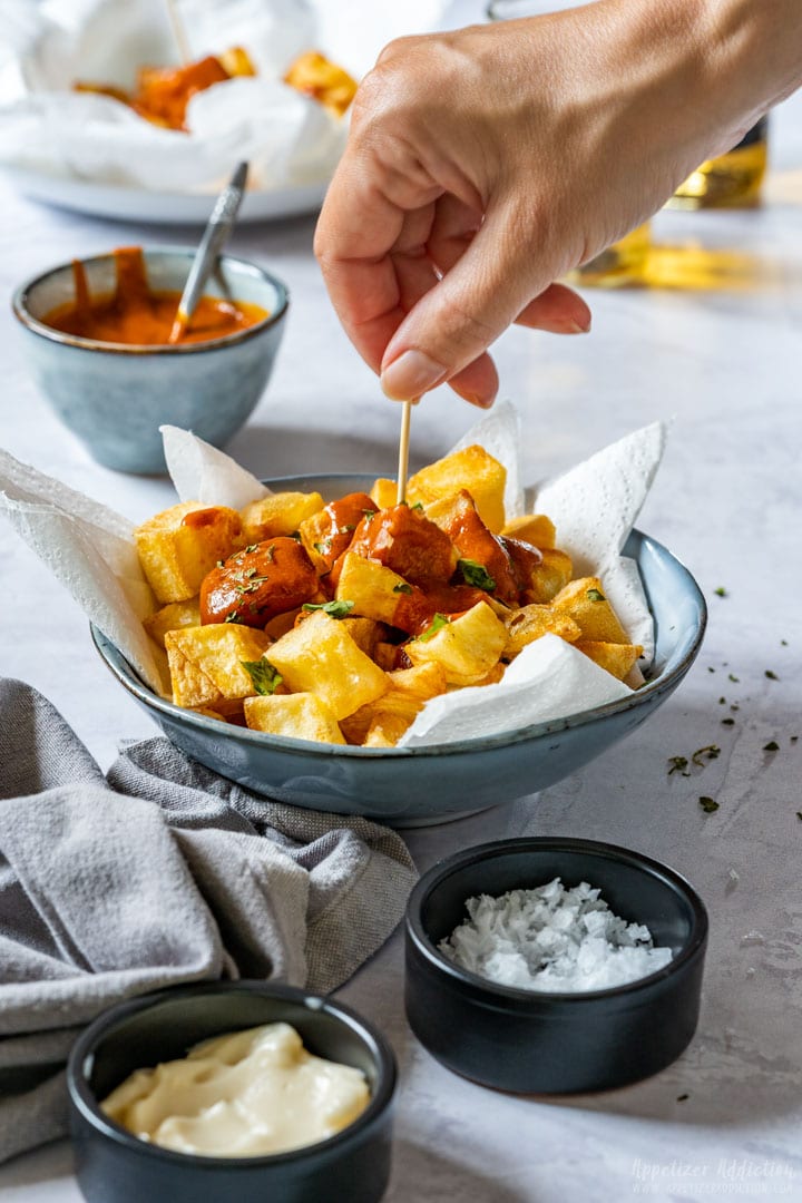 Eating patatas bravas with wooden stick