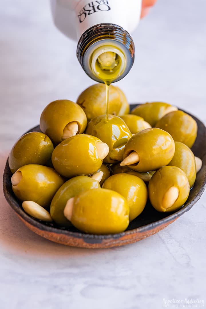 Pouring olive oil over stuffed green olives with almonds