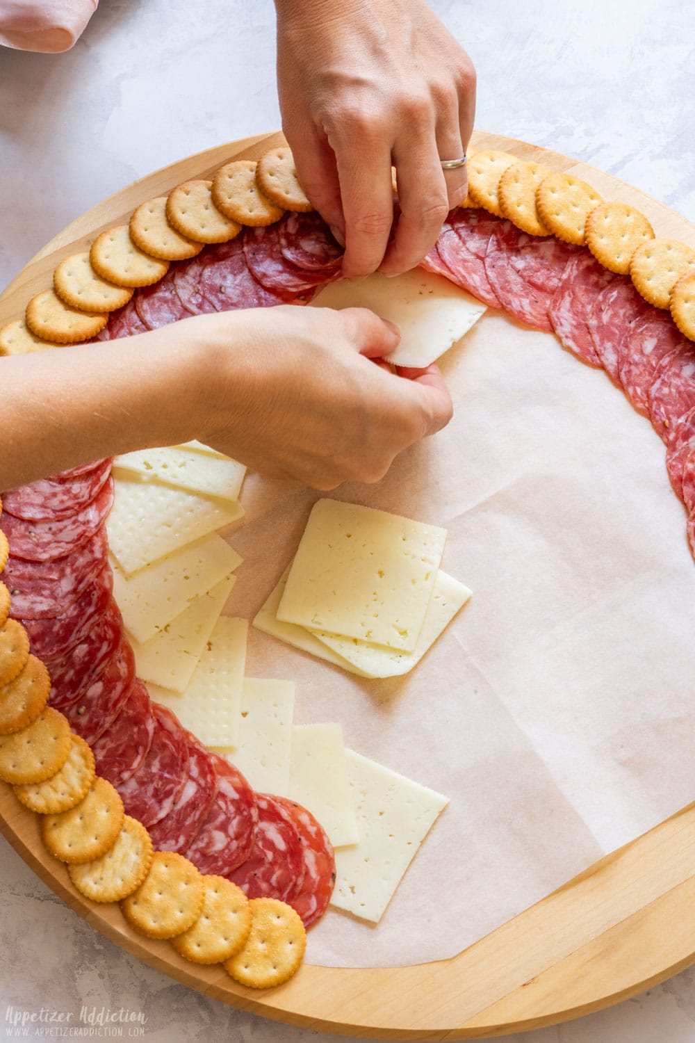 Placing the sliced cheese under the salami slices.