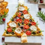 Creative Christmas tree pizza with salami, olives, tomatoes and mozzarella cheese.