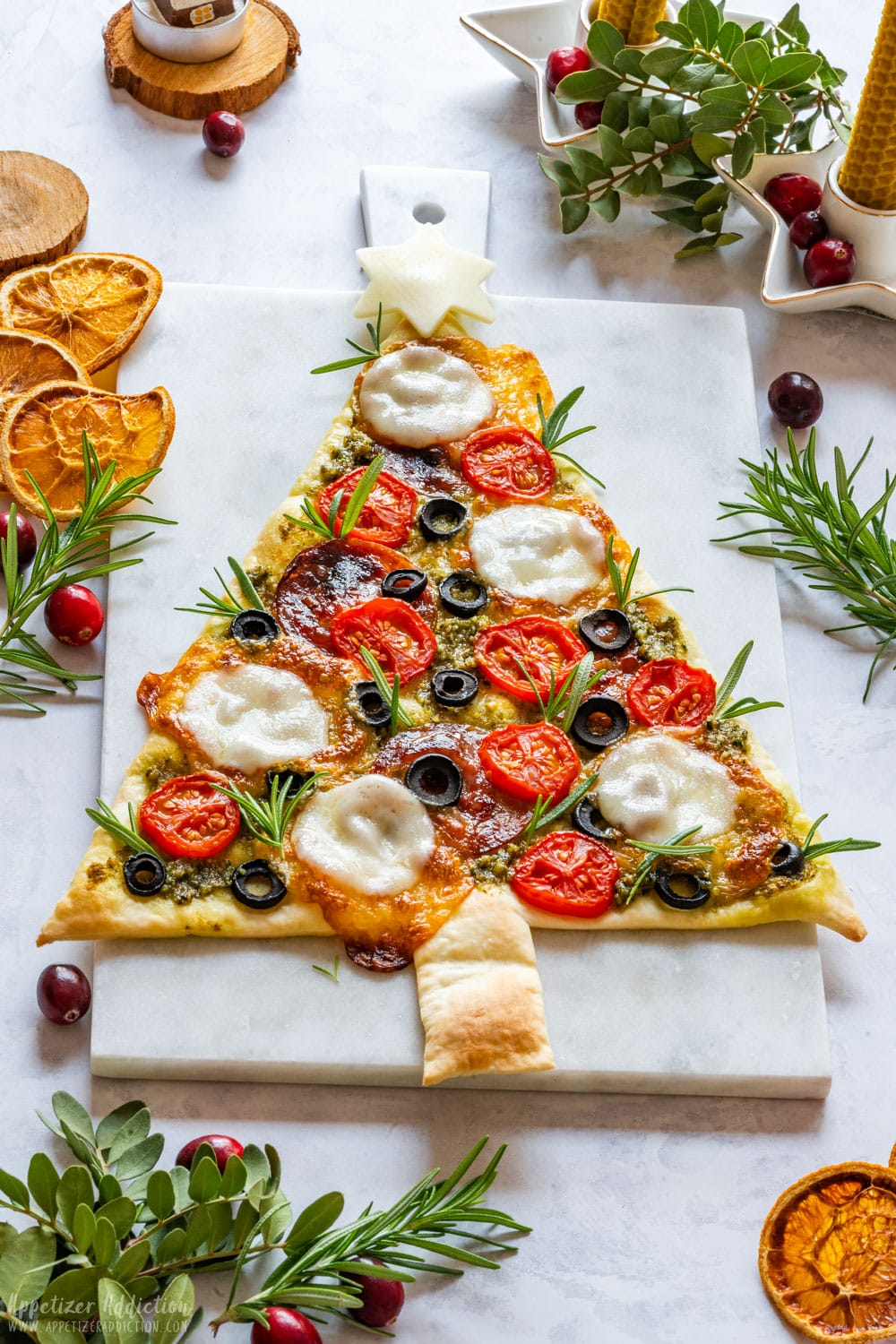 Creative Christmas tree pizza with salami, olives, tomatoes and mozzarella cheese.