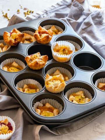 Freshly baked puff pasty brie bites on a muffin tray.