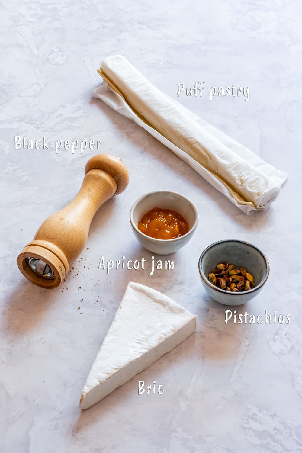 Ingredients of brie bites: puff pastry, brie, apricot jam, pistachios and black pepper.
