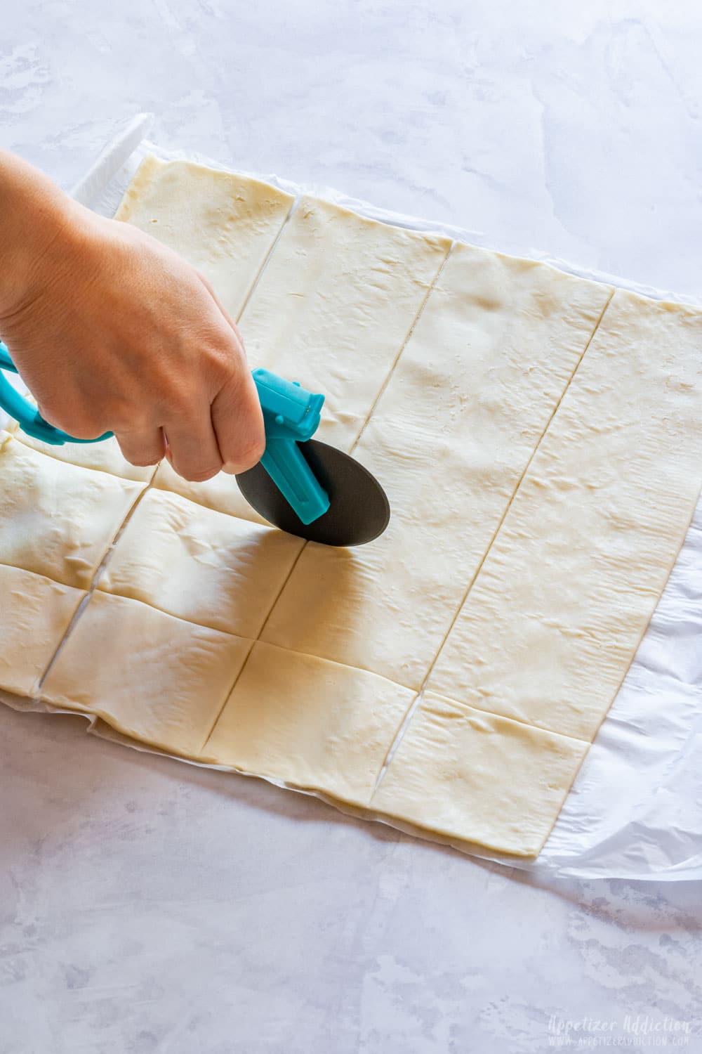 Cutting puff pastry into squares.