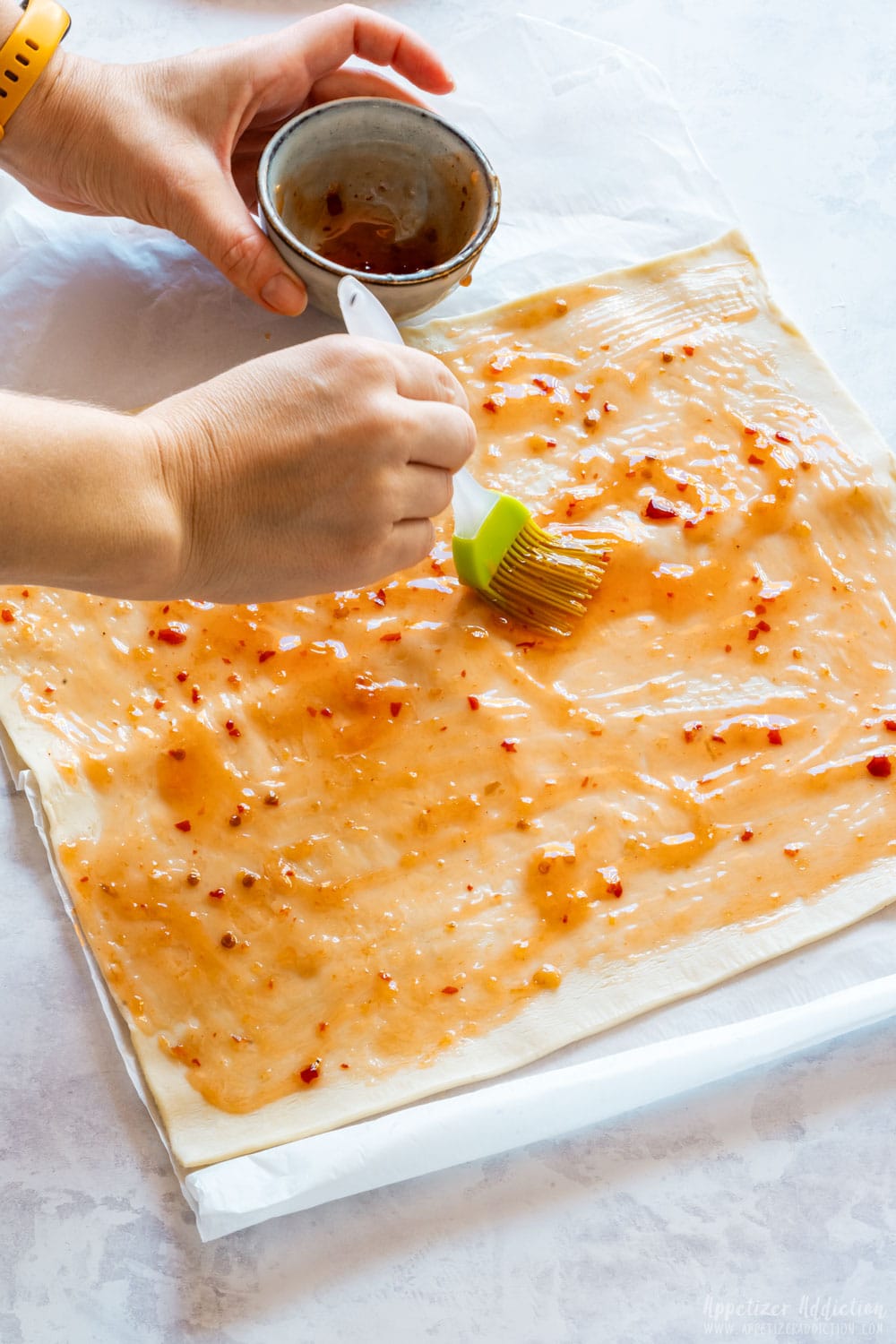 Spreading the sweet chili sauce on puff pastry.