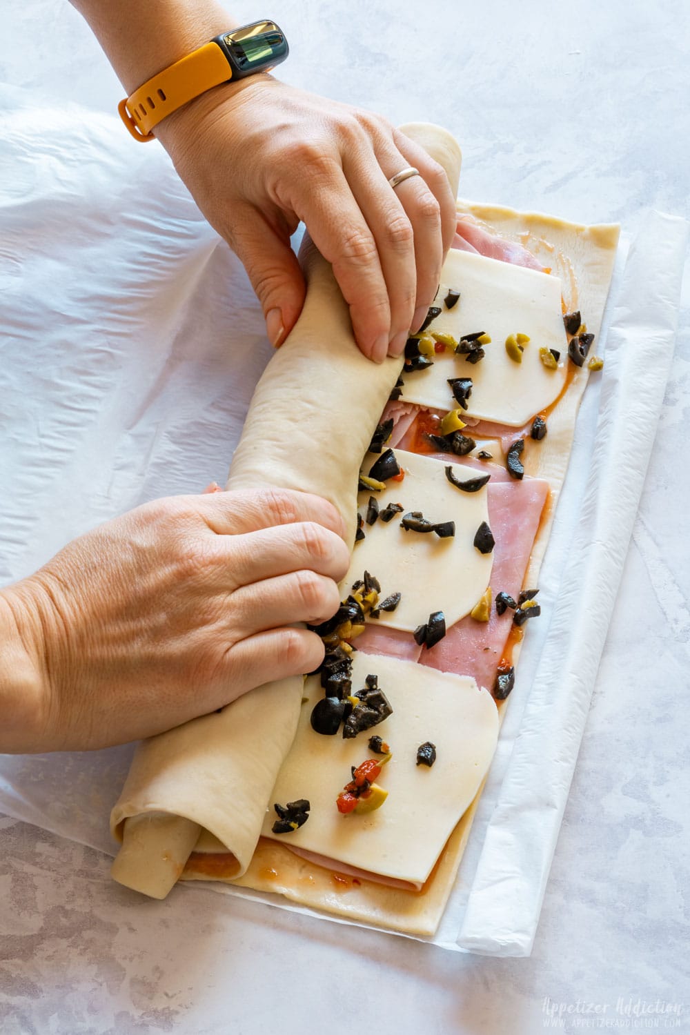 Rolling puff pastry with ham, cheese and olives.