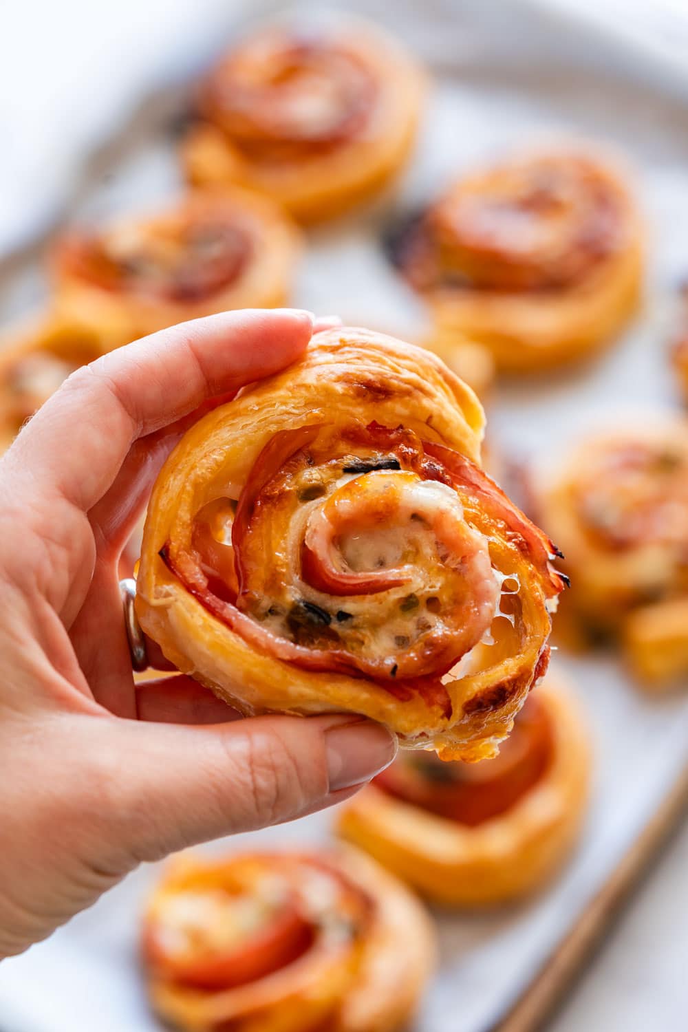 Holding puff pasty pinwheel with ham and cheese.