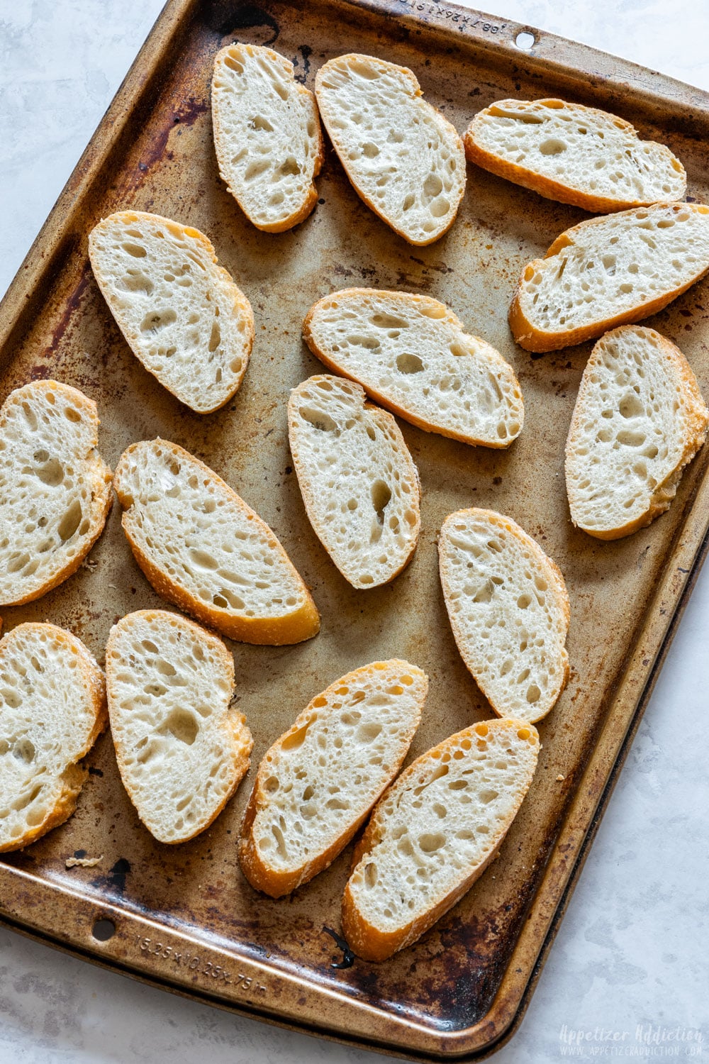 French baguette slices on the baking tray before toasting.