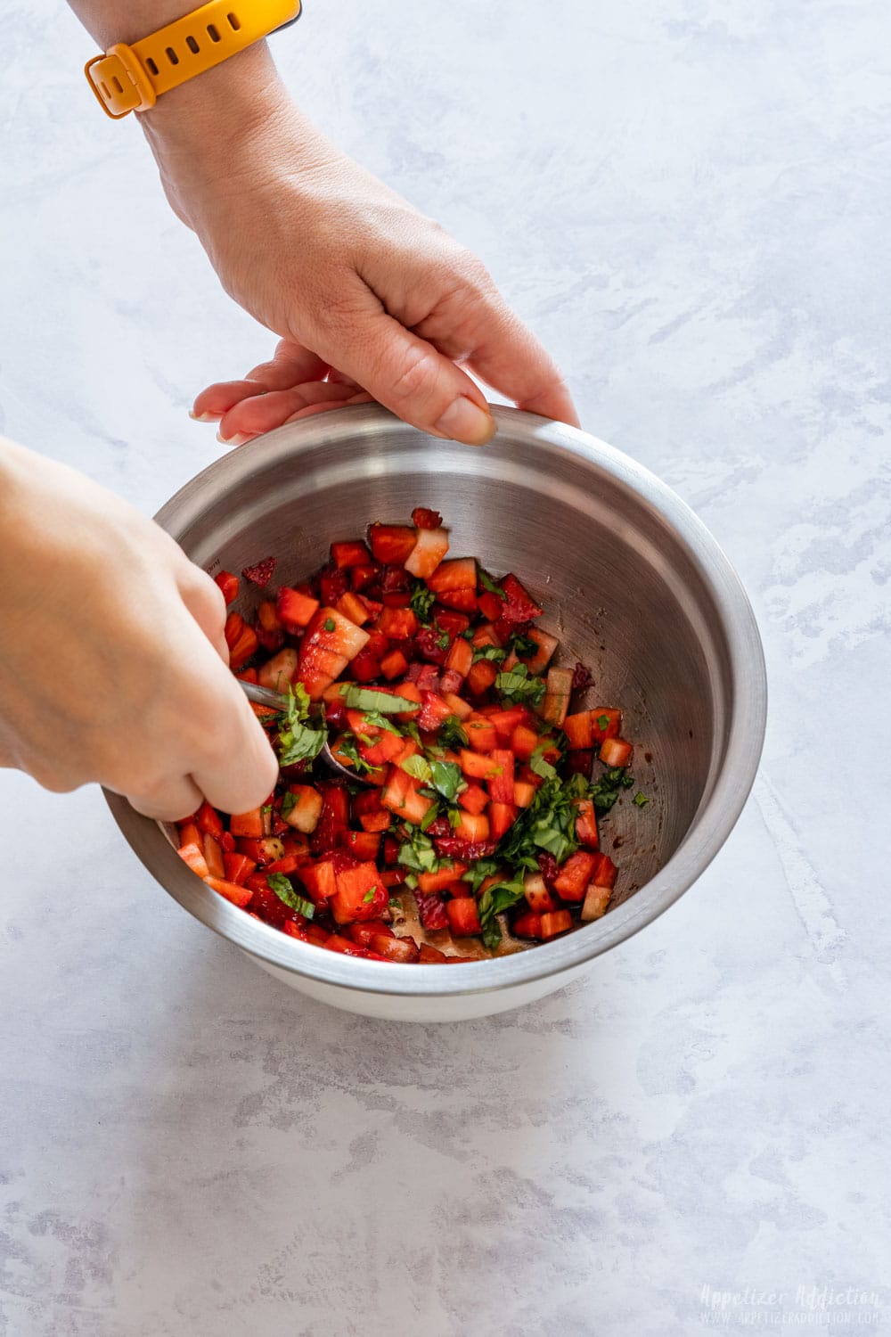 Mixing in the bowl topping for bruschetta.