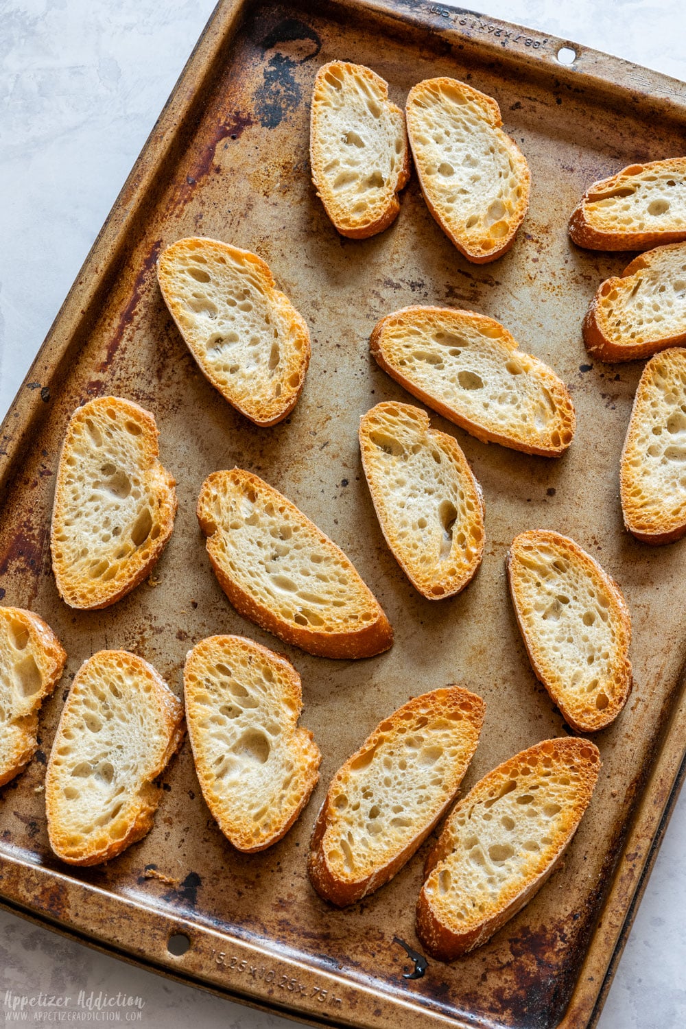 French baguette slices on the baking tray after toasting.