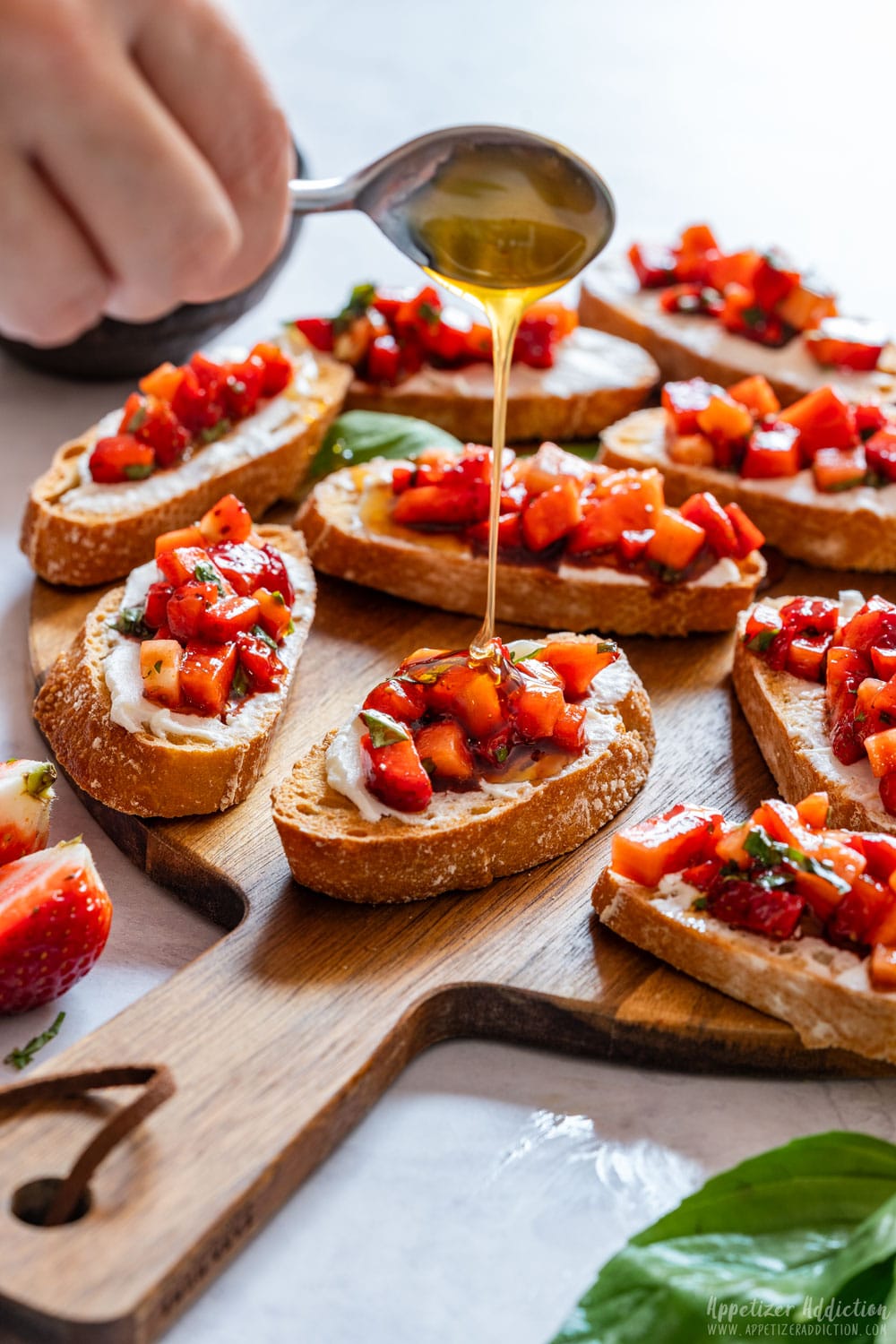 Drizzling honey on freshly made strawberry bruschetta.