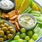 Close-up of snack board with green vegetables and fruits with dip.