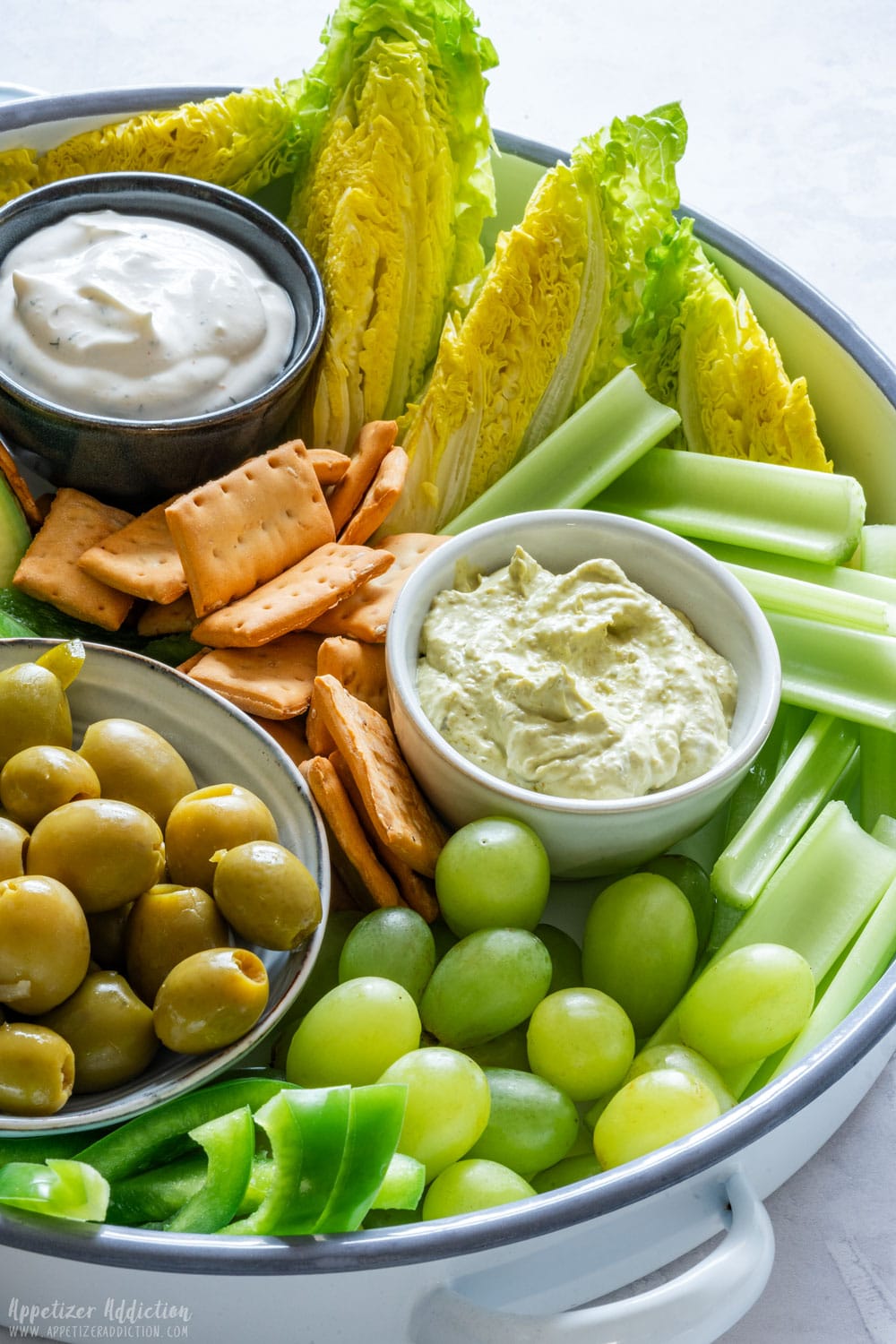Close-up of snack board with green vegetables and fruits with dip.