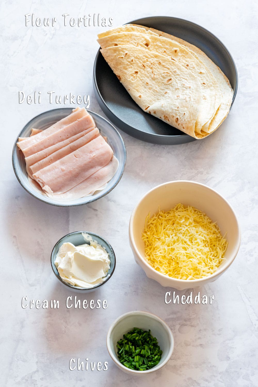Ingredients of turkey pinwheels: flour tortillas, cream cheese, deli turkey, cheddar and chives.