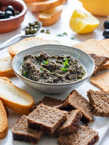 Homemade olive tapenade with breads and black olives.