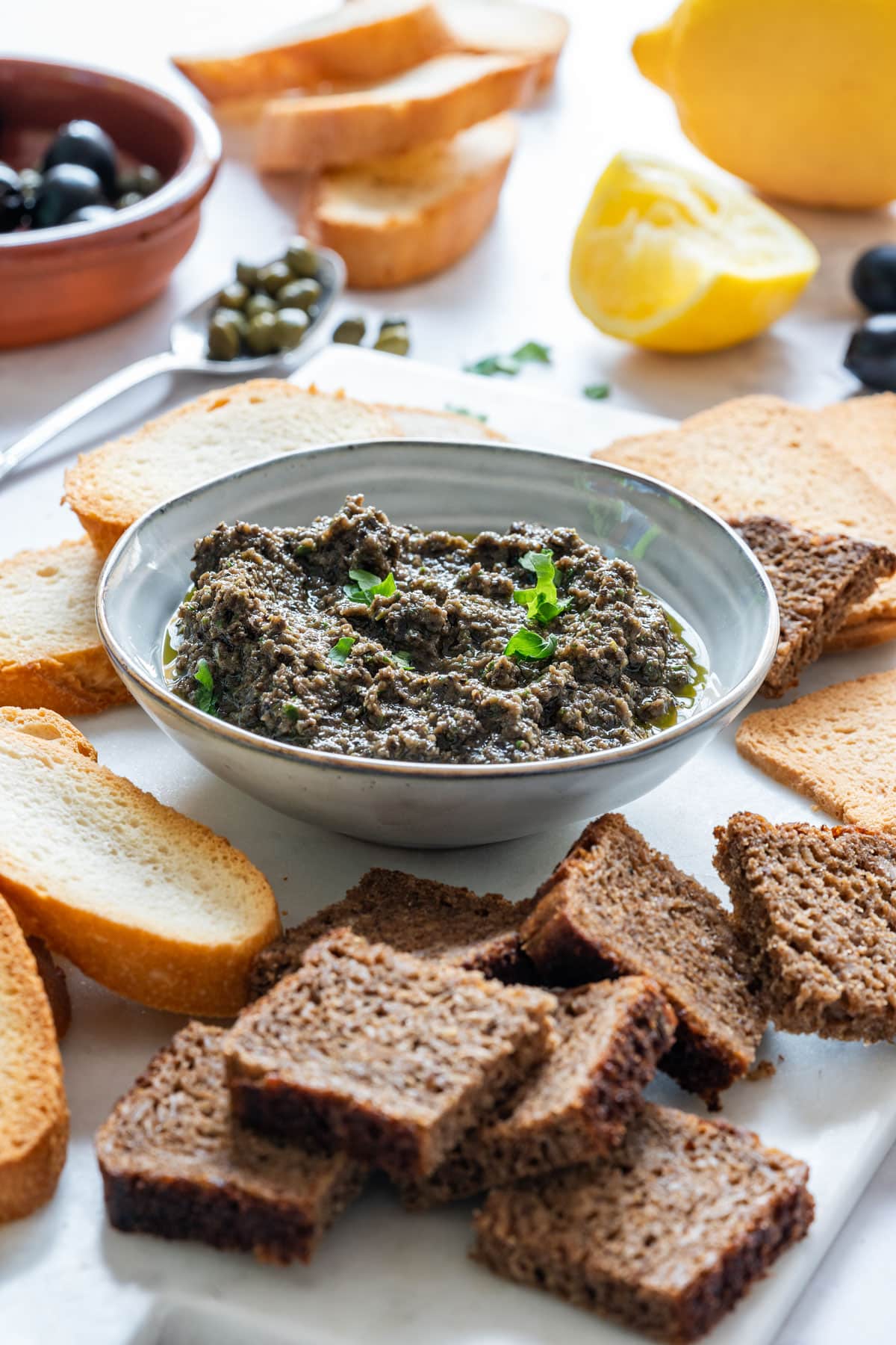 Homemade olive tapenade with breads and black olives.