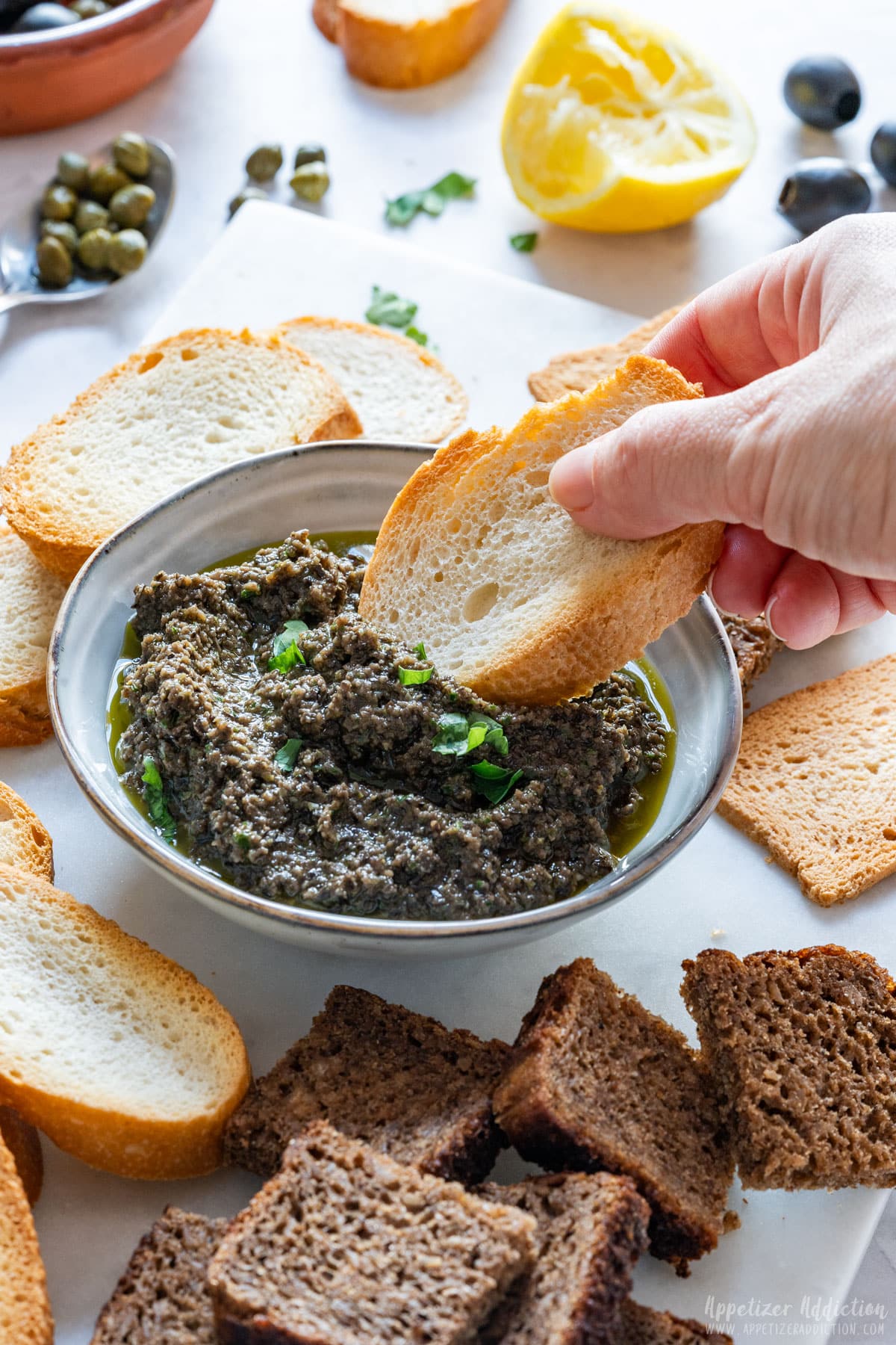 Scooping black olive tapenade with crostini.