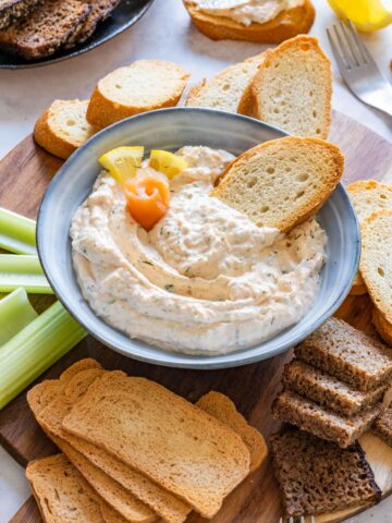 Bowl of homemade smoked salmon dip with lemon and toasted bread slices.