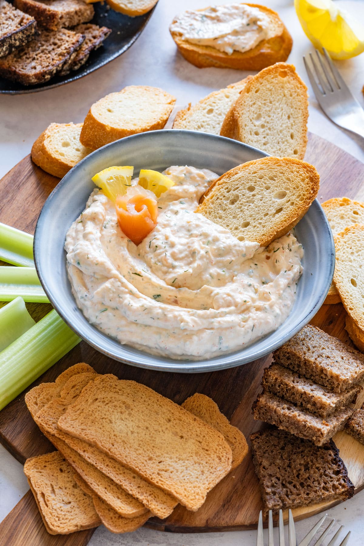 Bowl of homemade smoked salmon dip with lemon and toasted bread slices.