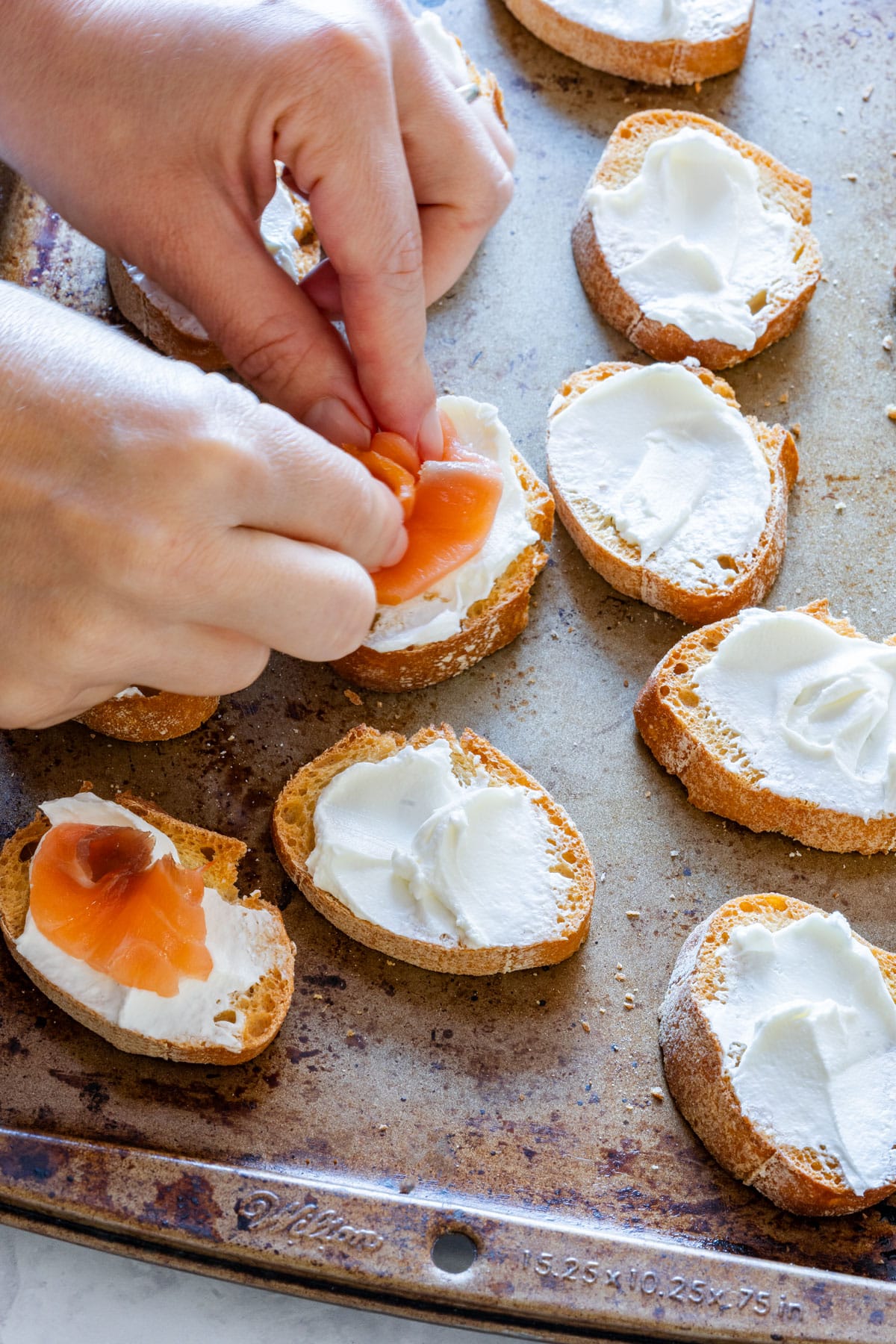 Showing how to make crostini with smoked salmon and cream cheese.