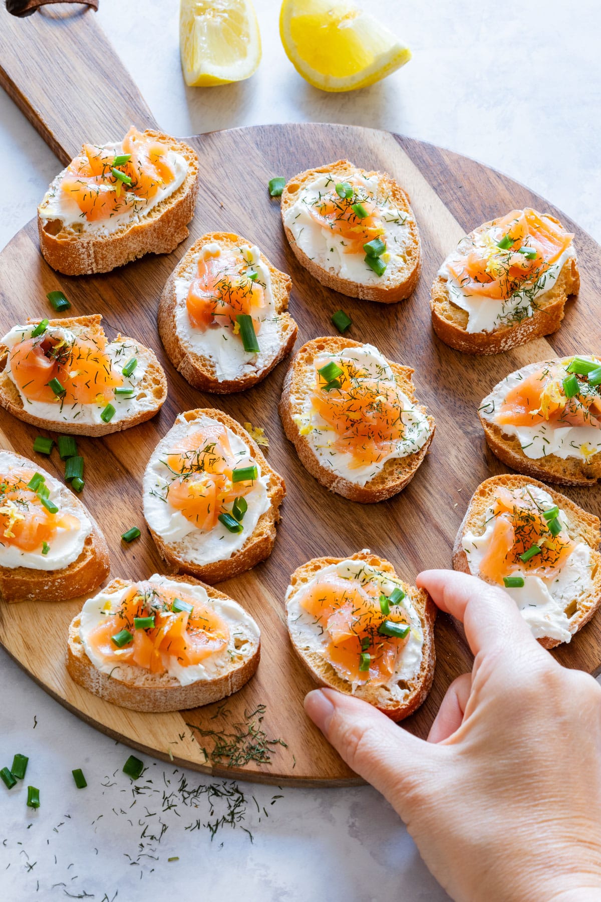 Woman hand taking bite-size appetizer with smoked salmon and cream cheese.