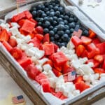 Red, white and blue fruit platter shaped like an American flag with watermelon, strawberries, blueberries, coconut and mini marshmallows for a 4th of July party.