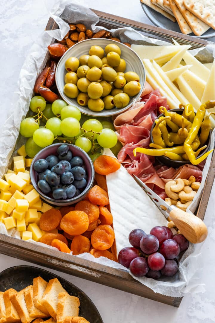 A beautifully arranged charcuterie board with variety of cheeses, cured meats and fruits.