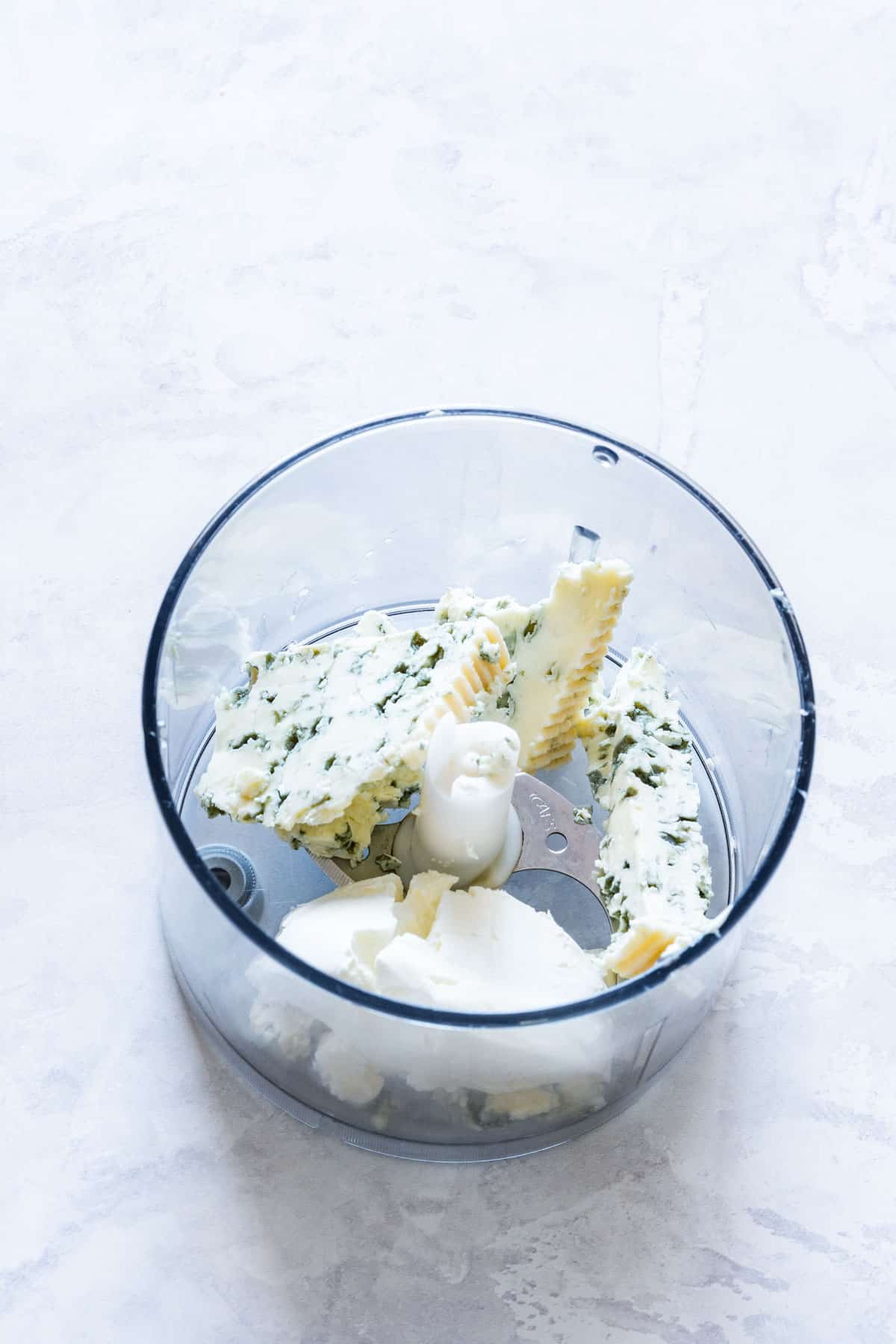 Chunks of blue cheese and cream cheese in a food processor before blending.