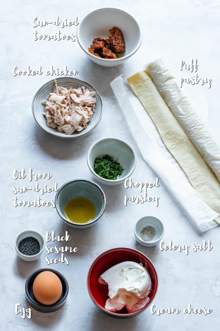 Overhead shot of ingredients for chicken puffs, including puff pastry, chicken, cream cheese and sun-dried tomatoes.