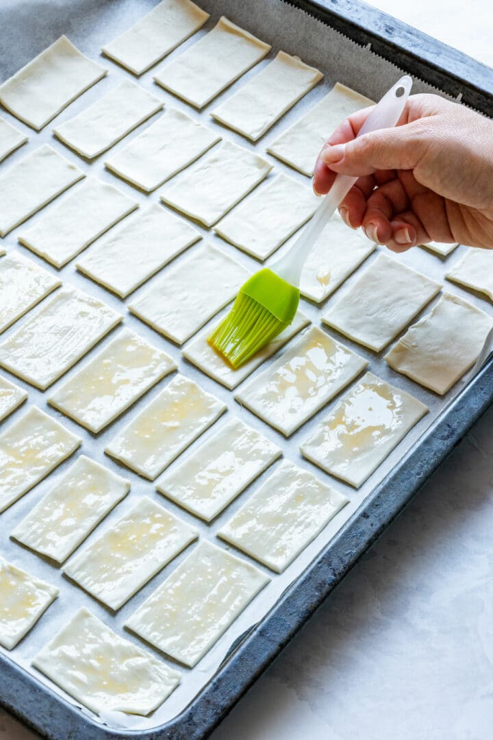 Puff pastry rectangles brushed with egg wash on a baking tray.