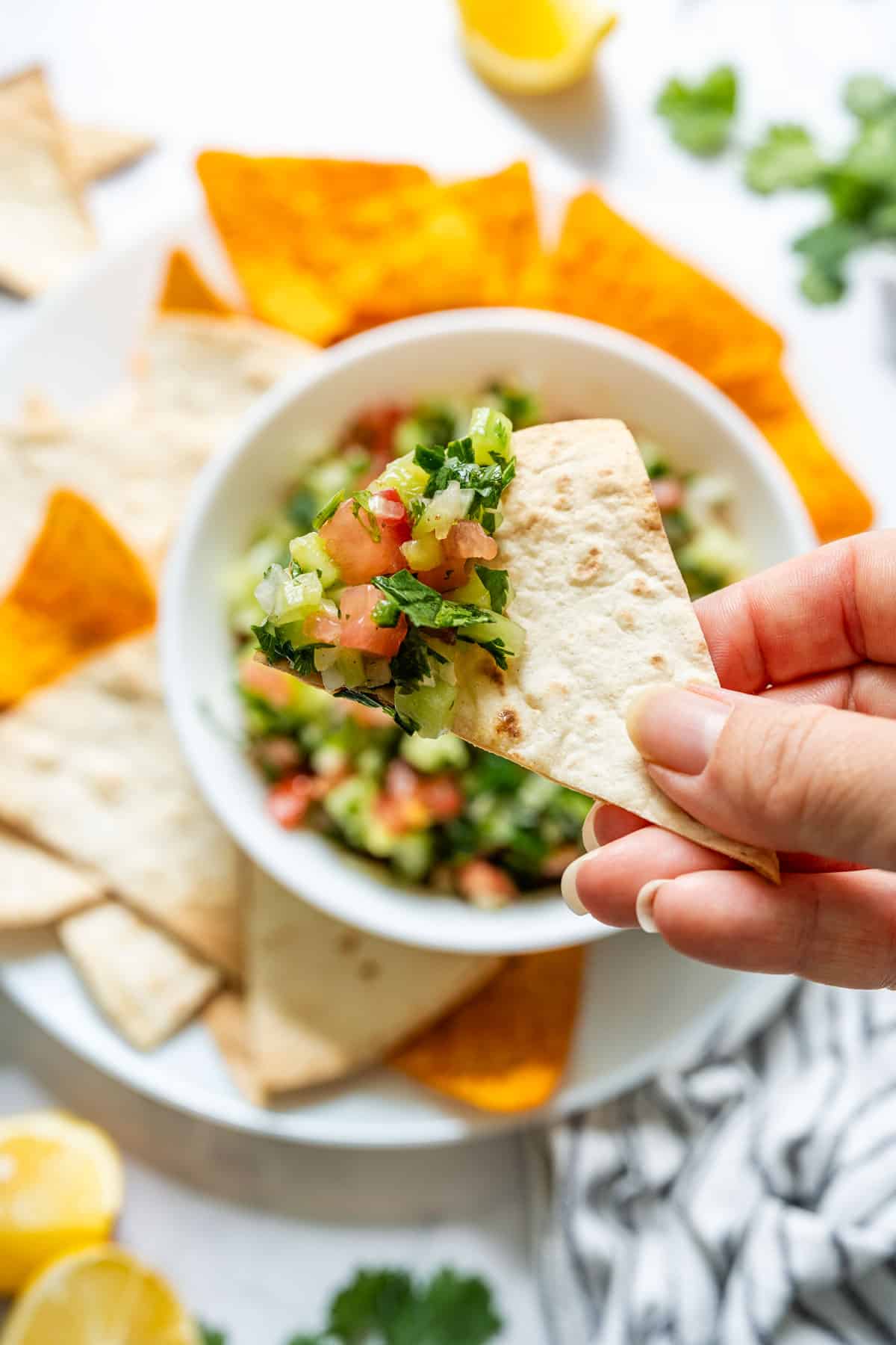 Close-up of a tortilla chip topped with fresh cucumber salsa.