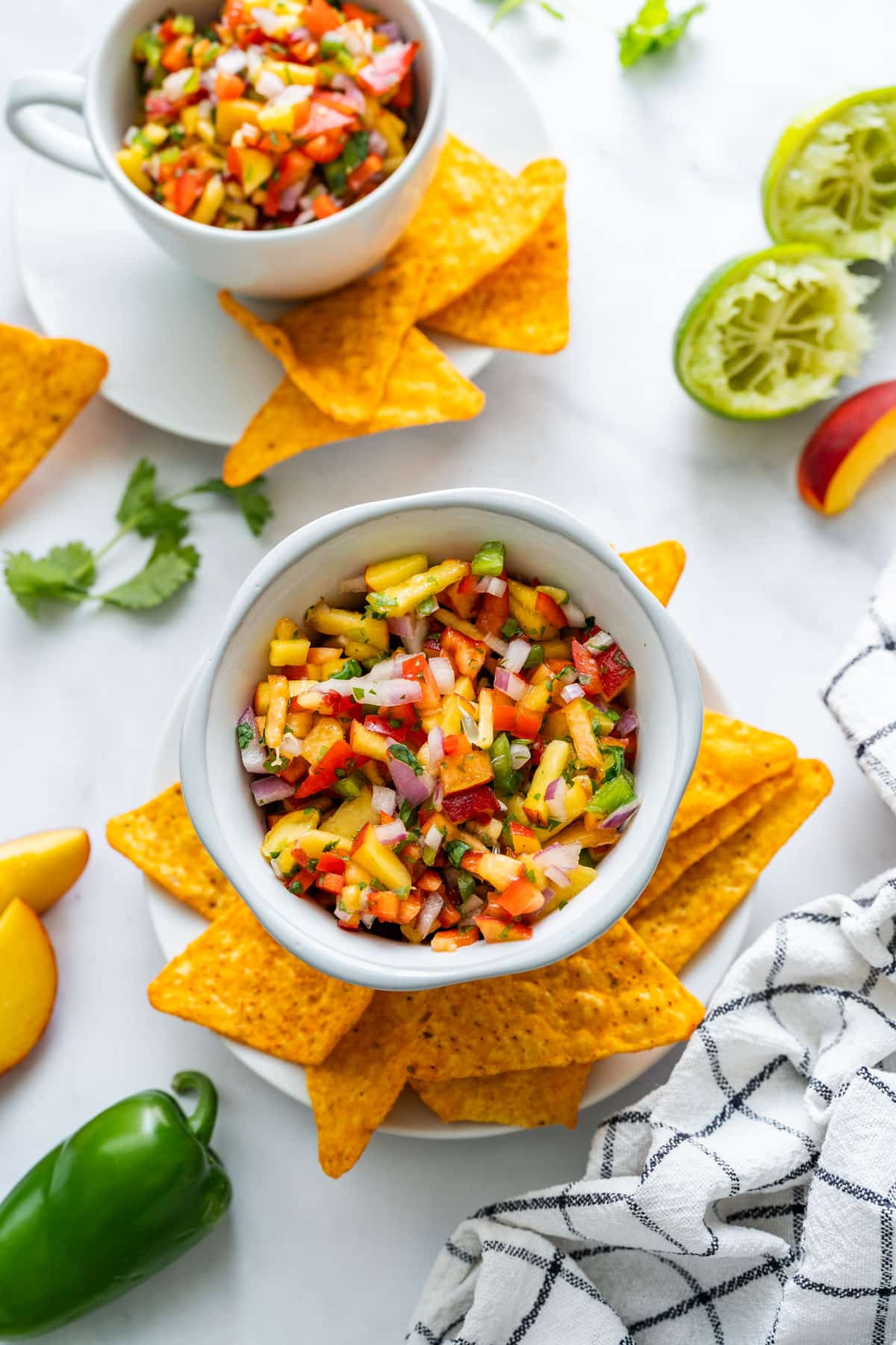 Bowls of peach salsa served with tortilla chips and fresh lime.