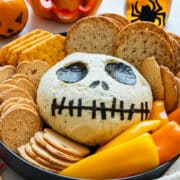 Finished Jack Skellington cheese ball on a serving platter with crackers and sliced peppers.