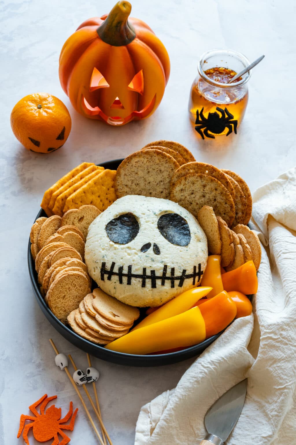 Overhead platter with Jack Skellington cheese ball, crackers, peppers and Halloween decor.