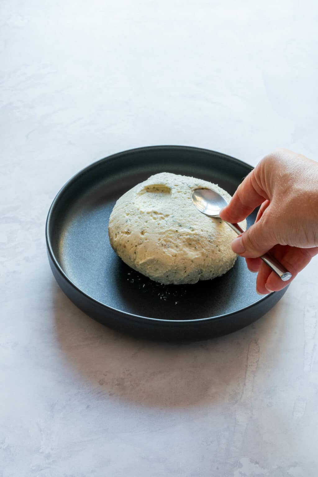 Shaping the cheese ball and creating eye sockets with a spoon.