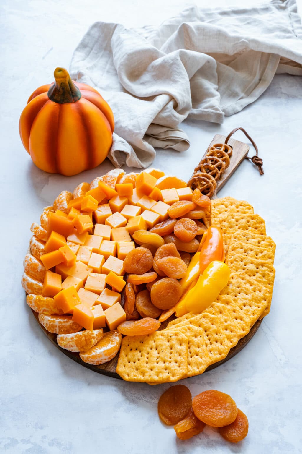 Finished fall cheese board on marble with linen and a decorative pumpkin.