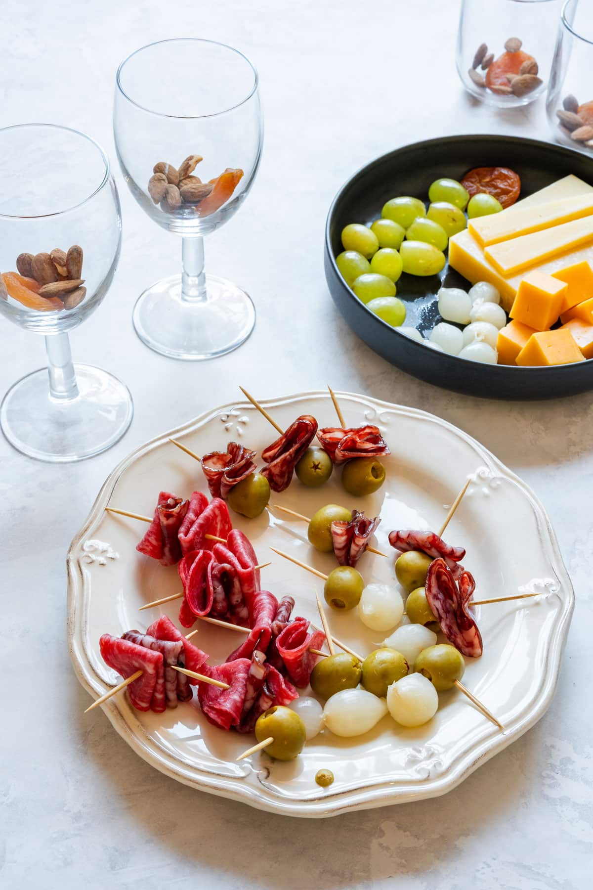 Making charcuterie cup skewers on toothpicks with olives, pickled onions and salami before assembling the cups.