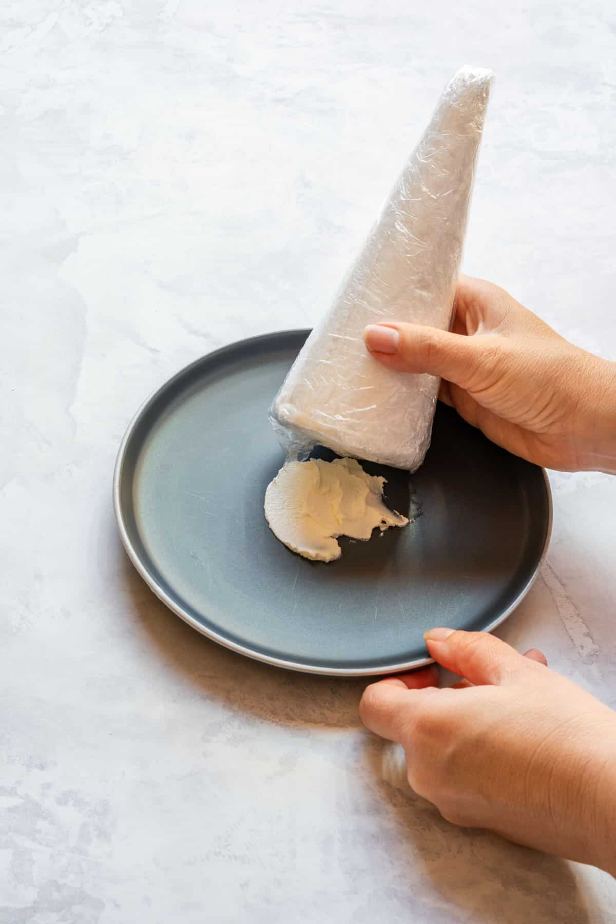 Wrapped cone being pressed into a dollop of cream cheese in the center of a serving plate to help it stand.