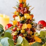 Christmas charcuterie tree centerpiece topped with a cheese star and rosemary, styled with greenery, lights and candles.