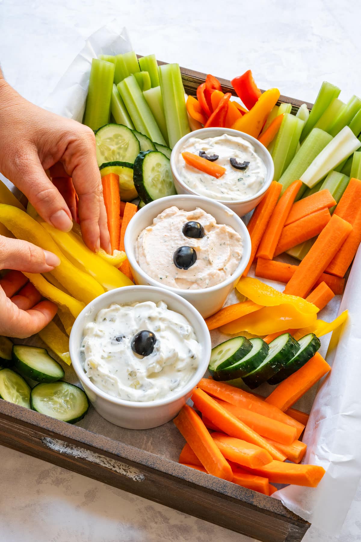 Arranging yellow bell pepper strips and other vegetables around the dip bowls while building the festive Christmas veggie tray.