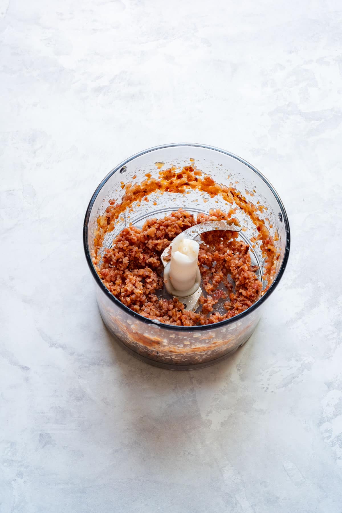 Finely chopped bacon in a food processor bowl.